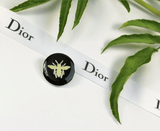 Christian Dior Dior Bee Pin with black background and white bee