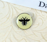 Christian Dior Dior Bee Pin with cream background and black bee